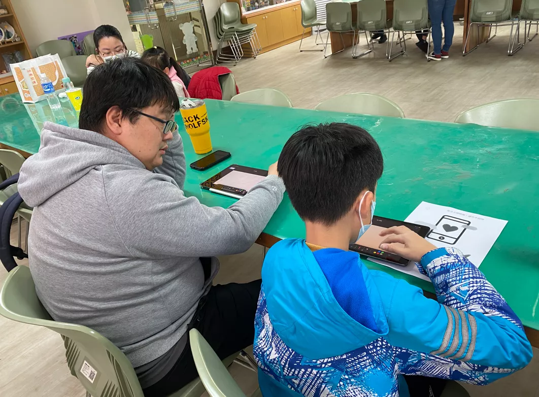 學員和孩子討論平板的繪畫內容。