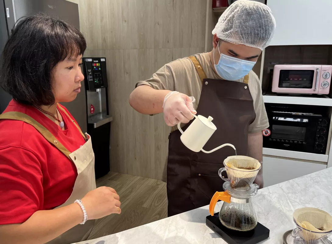 小育(右)在伊甸教保員莊嫚婷(左)的指導與陪伴下,逐漸熟悉手沖咖啡的技巧。