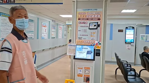 玉鑾志工於批價機前指引病患及家屬